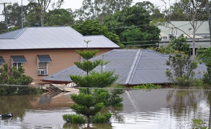 Floods inundating several homes with only the roof tiles visible of the one in the centre of the picture 